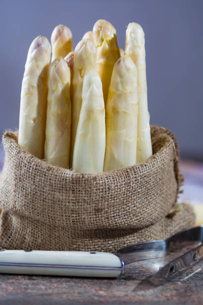 istock Spring season - fresh white asparagus in burlap sack on granite plank background 669394596