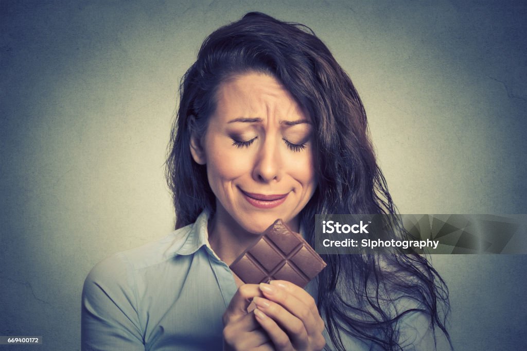 sad young woman tired of diet restrictions craving sweets chocolate Portrait sad young woman tired of diet restrictions craving sweets chocolate isolated on gray wall background. Human face expression emotion. Nutrition concept. Feelings of guilt Emotional Stress Stock Photo