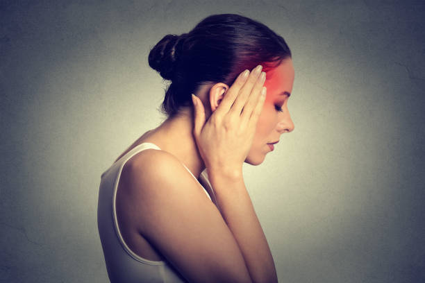 Woman having headache with her head in her hands isolated on gray wall background
