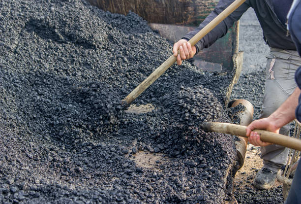 istock Asphalt workers with a shovel filling wheelbarrow with asphalt 2 669400356