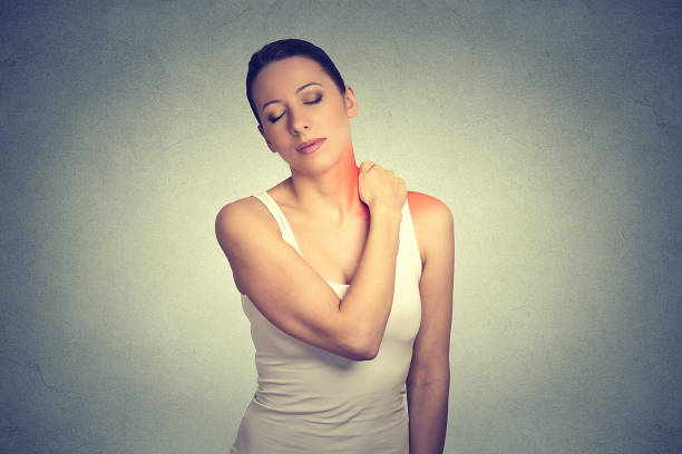 dolor. mujer con cuello hombro doloroso de color rojo aislado sobre fondo de pared gris - rotator cuff fotografías e imágenes de stock