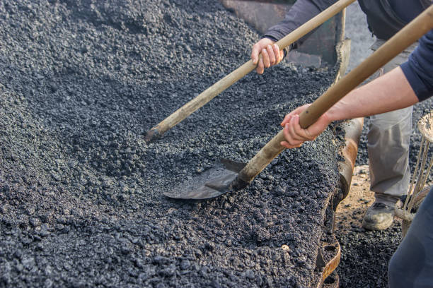 istock Asphalt workers with a shovel filling wheelbarrow with asphalt 3 669402680