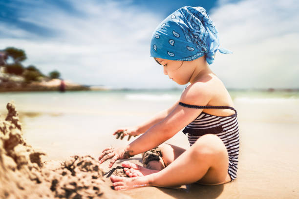 Cute girl building sand castle on tropical beach