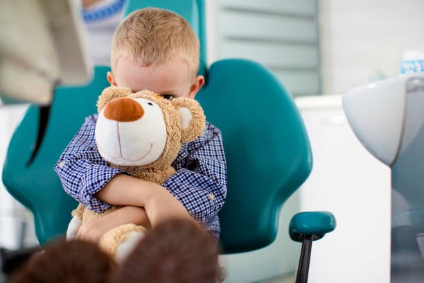 kleiner junge hielt einen teddybär in seinen armen zahnärzte büro - human teeth little boys behavior expressing negativity stock-fotos und bilder