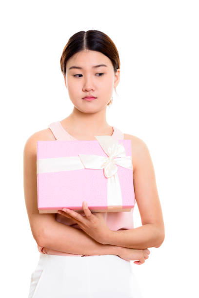 istock Studio shot of young beautiful Asian woman holding gift box while thinking 669458724