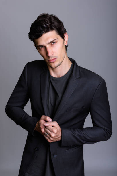 istock Young handsome businessman holding jacket and looking at camera against gray background 669462110