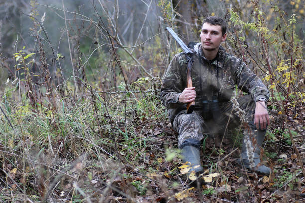 istock Man in camouflage and with guns in a forest belt on a spring hun 669474362