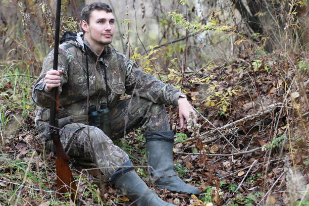 istock Man in camouflage and with guns in a forest belt on a spring hun 669474378