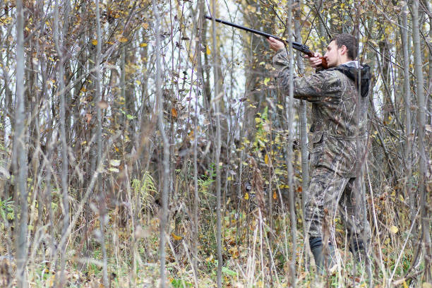 istock Man in camouflage and with guns in a forest belt on a spring hun 669474412