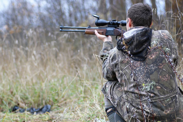 istock Man in camouflage and with guns in a forest belt on a spring hun 669474492