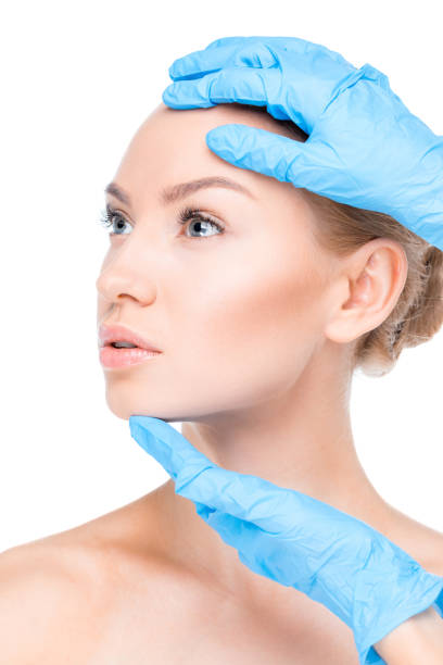 cosmetologist examining face of patient