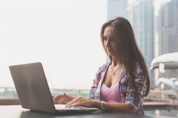 istock Young woman using a laptop working outdoors. Female looking at the screen and typing on keyboard. 669497924