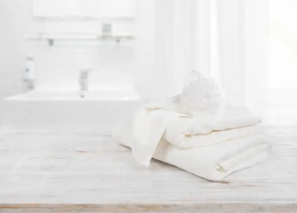 Photo of Fluffy towels and wisp of bast over blurred bathroom background