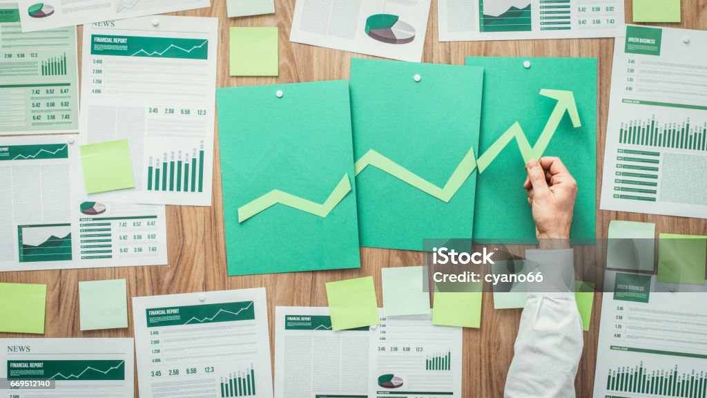 Financial success and green business Businessman composing a successful financial chart with arrow going up, he is using green paper cuts, eco business and financial success concept Sustainable Resources Stock Photo