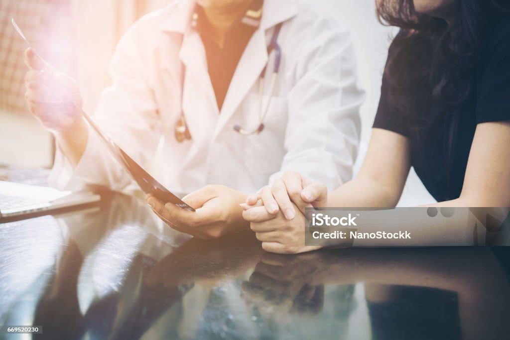 Doctor and patient consulting on a table Doctor and patient consulting on a table about women health. Medical concept.  Selective focus at patient's hands. Doctor Stock Photo