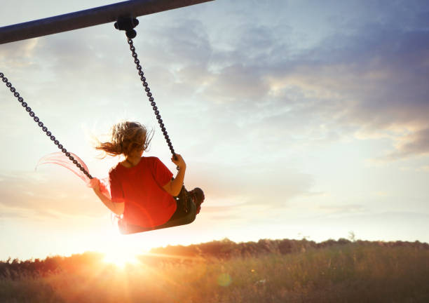 Little girl enjoying swinging Child enjoying swinging in sunset light swing stock pictures, royalty-free photos & images