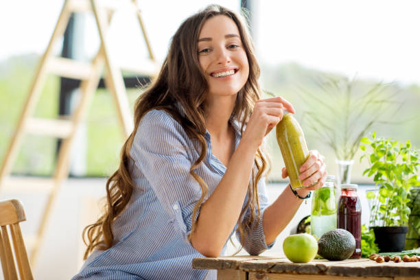 donna con cibo sano verde e bevande a casa - women juice drinking breakfast foto e immagini stock