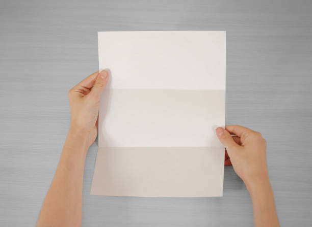 istock Hands holding blank white brochure booklet in the hand. Leaflet presentation. Pamphlet hand man. Show offset paper. Sheet template. Book in hands. Booklet folding design. Fold paper sheet display read 669541546