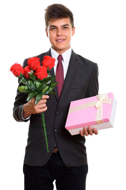istock Young happy businessman smiling while holding red roses and gift box ready for Valentine's day 669545400