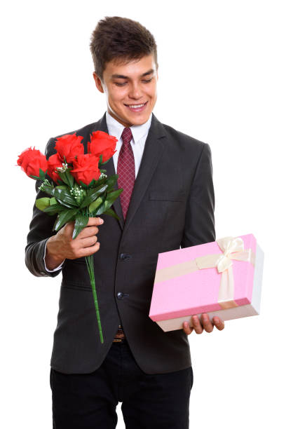 istock Young happy businessman smiling while holding red roses and looking at gift box ready for Valentine's day 669545406