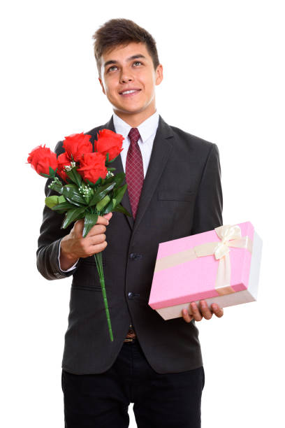 istock Thoughtful young happy businessman smiling while holding red roses and gift box ready for Valentine's day 669545408