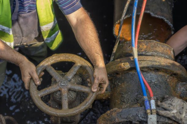 istock Industrial worker turning a valve on a large pipe 2 669545940