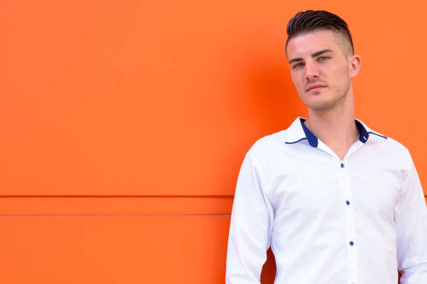 istock Young handsome man against orange concrete wall 669555686