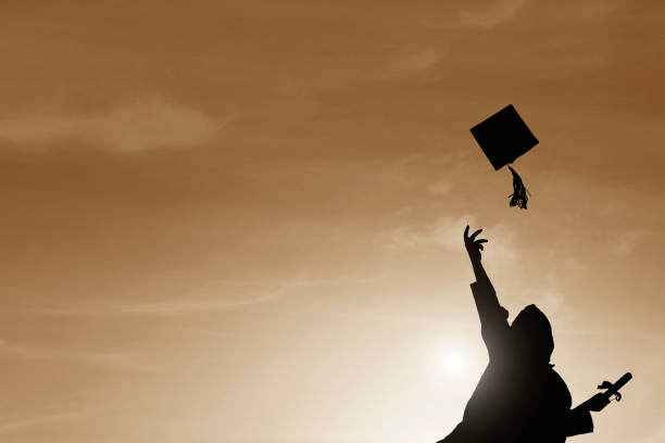 istock Graduate students tossing up hats over sky 669558040