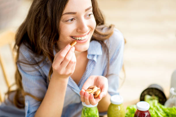 Woman eating nuts Closeup view from above of a woman eating brasil nuts with healthy food on the background nut stock pictures, royalty-free photos & images