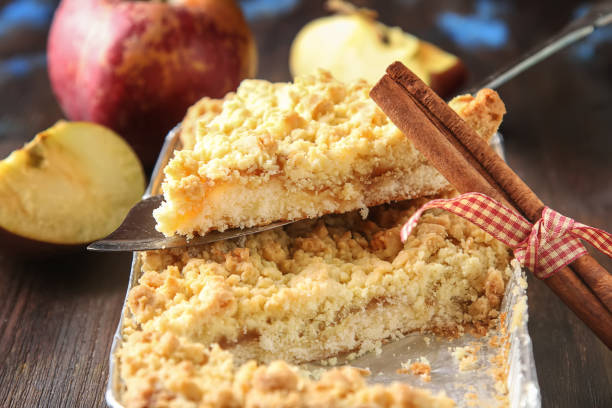 Homemade apple crumble crisp cake on white plate with autumn leaves on the background.