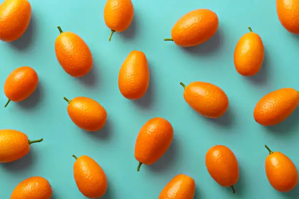 Flat lay pattern of fresh kumquats on a colorful background. Top view