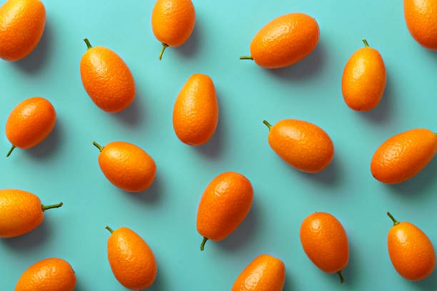 flat lay pattern of fresh kumquats on a colorful background. top view - kumquat imagens e fotografias de stock