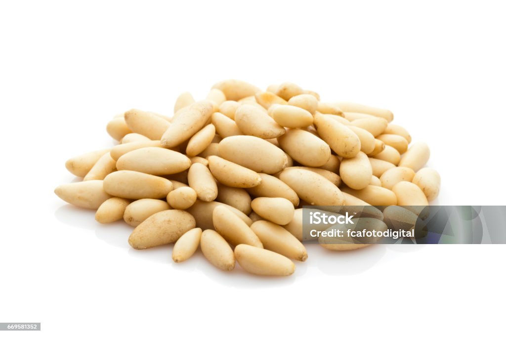 Pine nuts heap isolated on white background Front view of Pine nuts heap isolated on reflective white background.  DSRL studio photo taken with Canon EOS 5D Mk II and Canon EF 100mm f/2.8L Macro IS USM Pine Nut Stock Photo