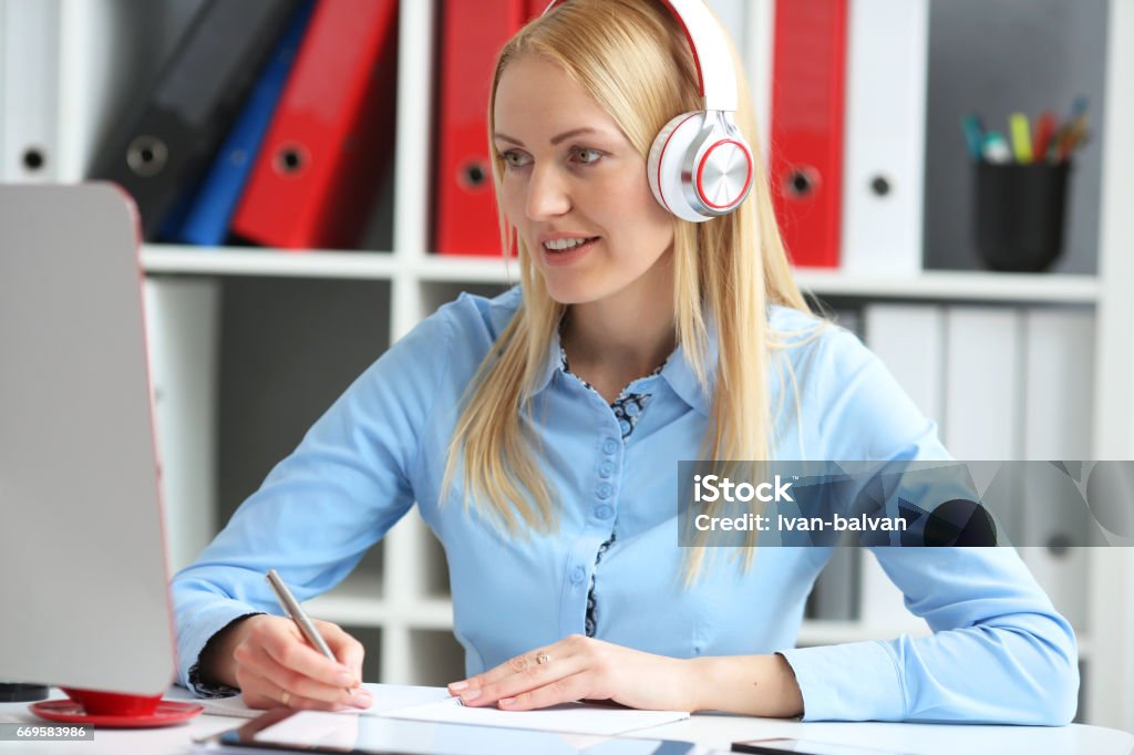 Mujer de negocios, estudiar en línea. Conferencia de escucha mira el monitor de escritorio. Él está sonriendo y haciendo notas - Foto de stock de Examen libre de derechos