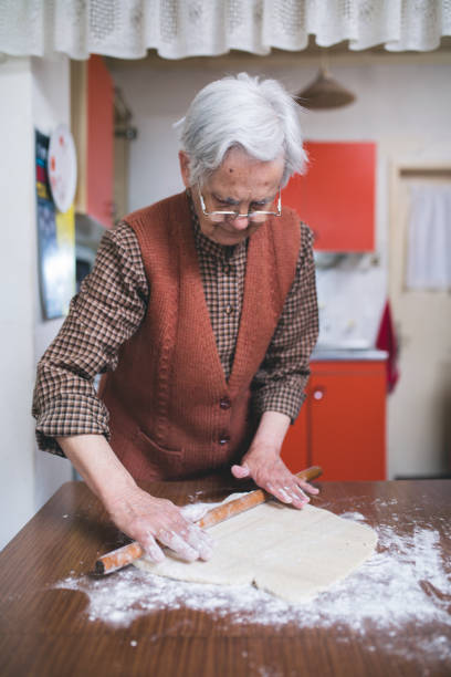 istock Senior woman baking pies in her home kitchen. Rolling dough using rolling pin. 669591518