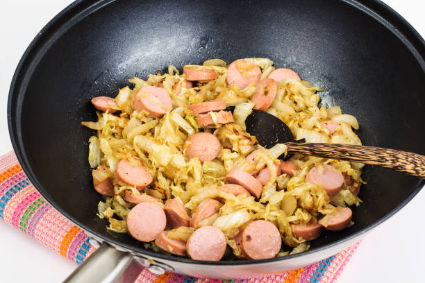 istock Stewed cabbage with sausages in frying pan over white background 669591620