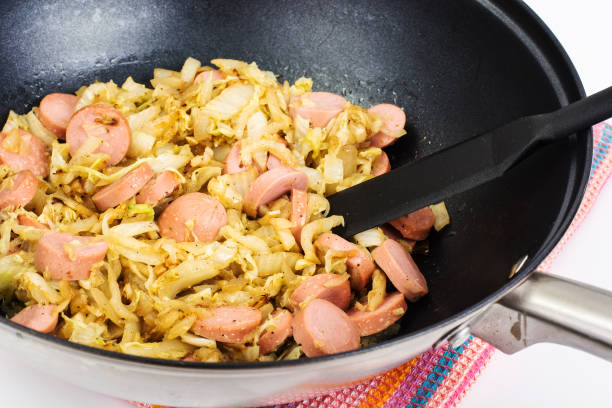 istock Stewed cabbage with sausages in frying pan over white background 669591722