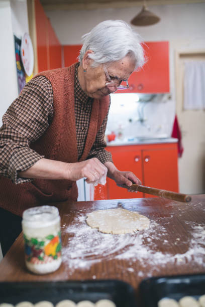istock Senior woman baking pies in her home kitchen. Rolling dough using rolling pin. 669596780
