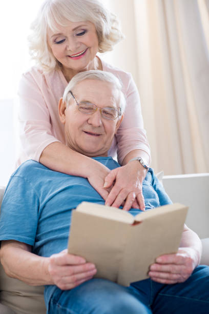 istock Happy senior couple hugging and relaxing, man reading book 669606644