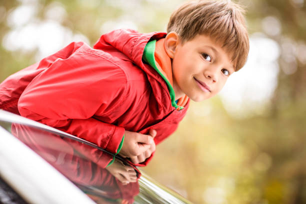 istock Cute little boy standing in car 669607646