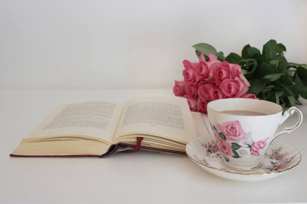 istock Tea in a vintage cup and saucer, roses and san open hardback book 669614082