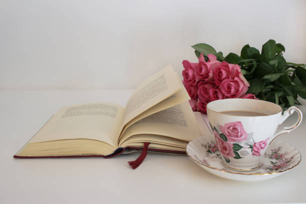 istock Tea in a vintage cup and saucer, roses and open hardback book 669614084