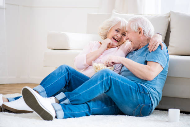 istock Happy senior couple eating popcorn and sitting on floor 669620320