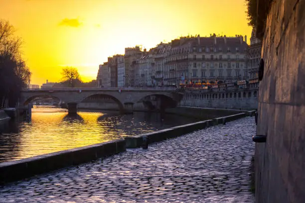 Between the Pont des Arts and the Pont Neuf in the heart of Paris, a small footpath runs along the edge of the Seine River. The path offers a view towards Notre Dame Cathedral and in midwinter, sunrise is almost above the water.
