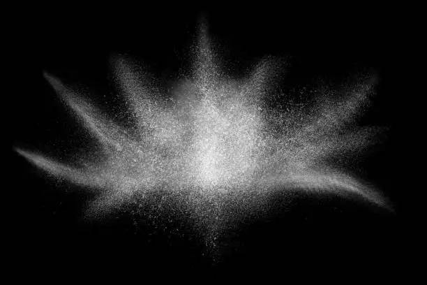Photo of Freeze motion of white powder exploding, isolated on black, dark background.