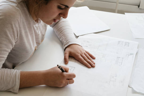 istock Young female architect working on sketches on desk 669634224