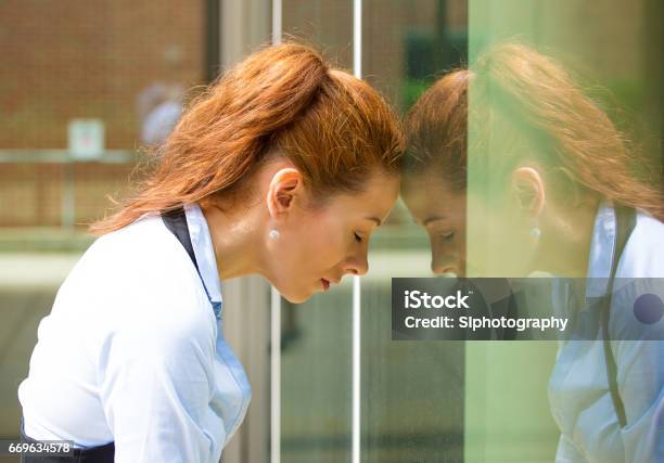 Closeup Portrait Unhappy Sad Young Business Woman Head On Window Bothered By Mistake Having Bad Headache Stock Photo - Download Image Now