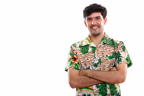 Studio shot of young happy Persian tourist man smiling with arms crossed horizontal shot