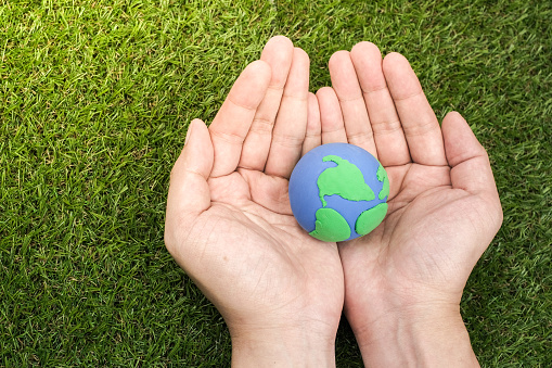 Globe ,earth made from clay in hand on green background. Concept Save green planet. Earth day holiday concept