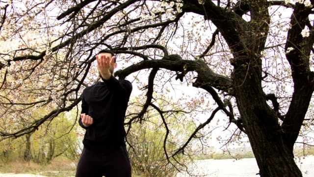 Young man practicing wing chun near the river